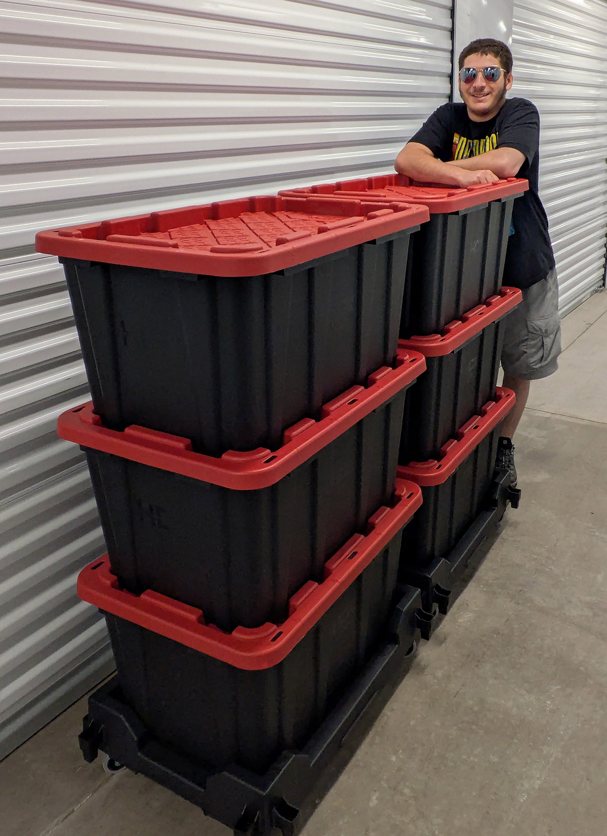 The son of Twin Cities Totes Rental husband & wife team Jen and Mykl pushing two stacks of moving totes on rolling bases.